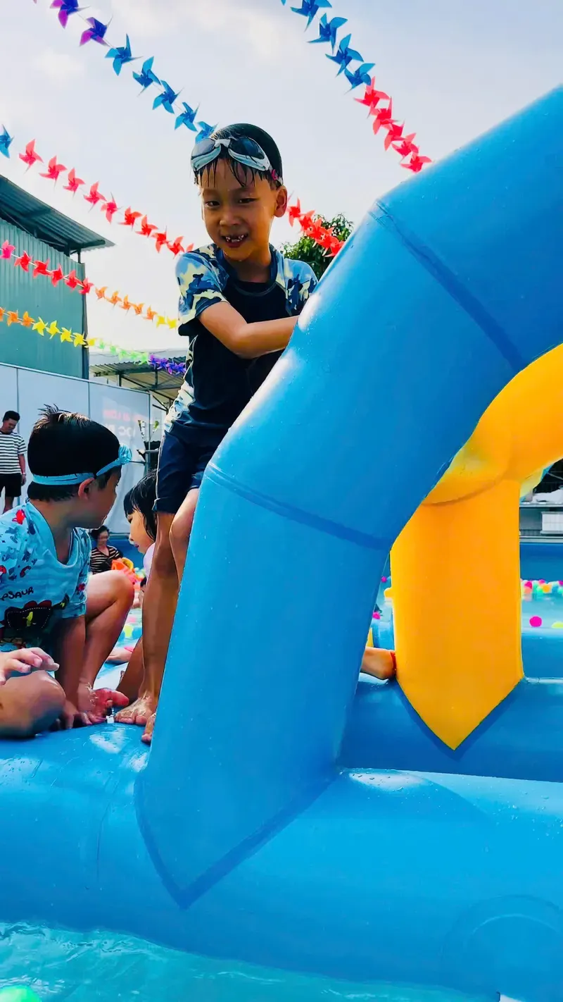 Học viên nhỏ tuổi cười tươi khi tập bơi với phao